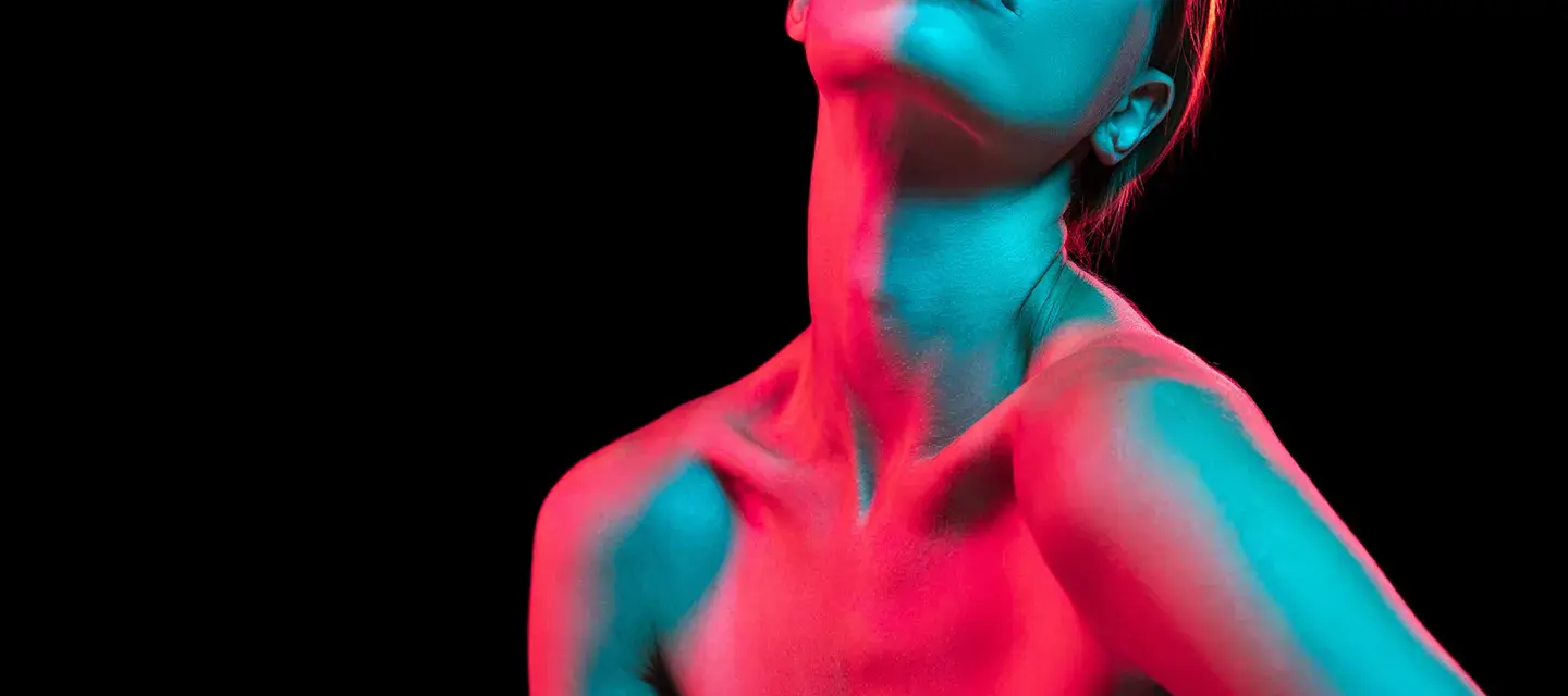 A womans neck and chest illuminated by red and green